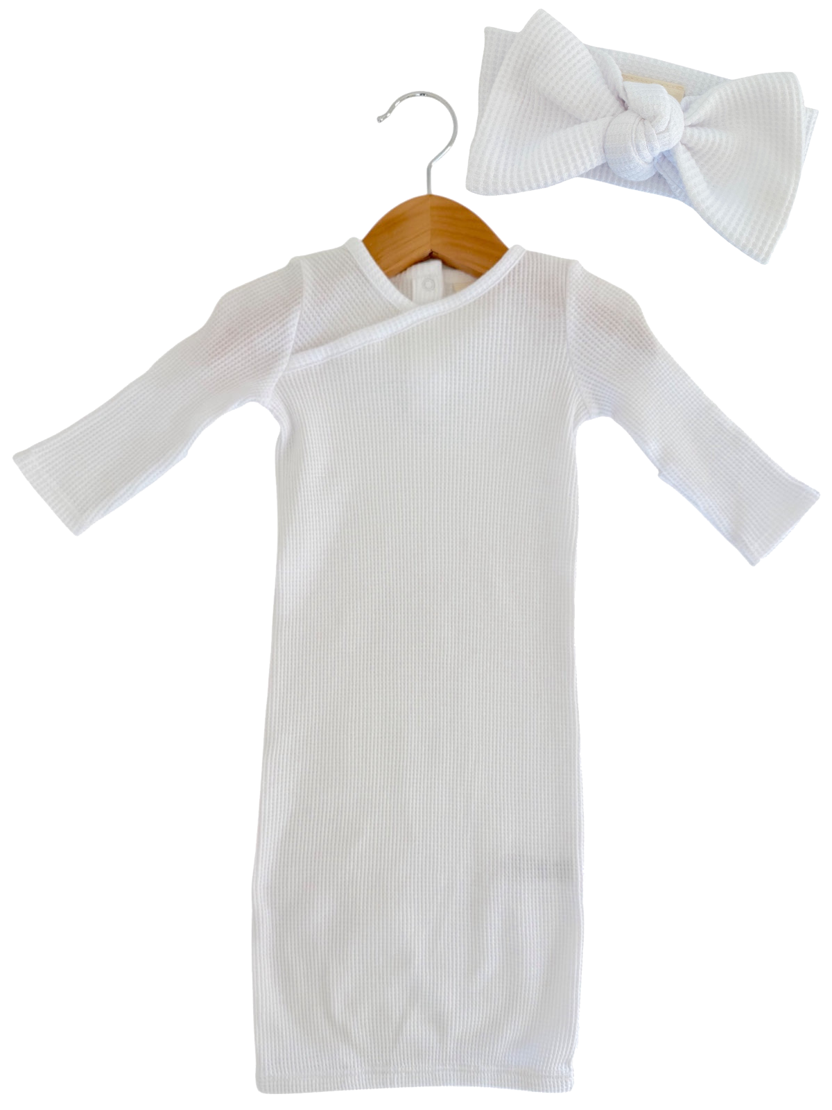 White ribbed dress with long sleeves and a matching bow headband, displayed on a wooden hanger.