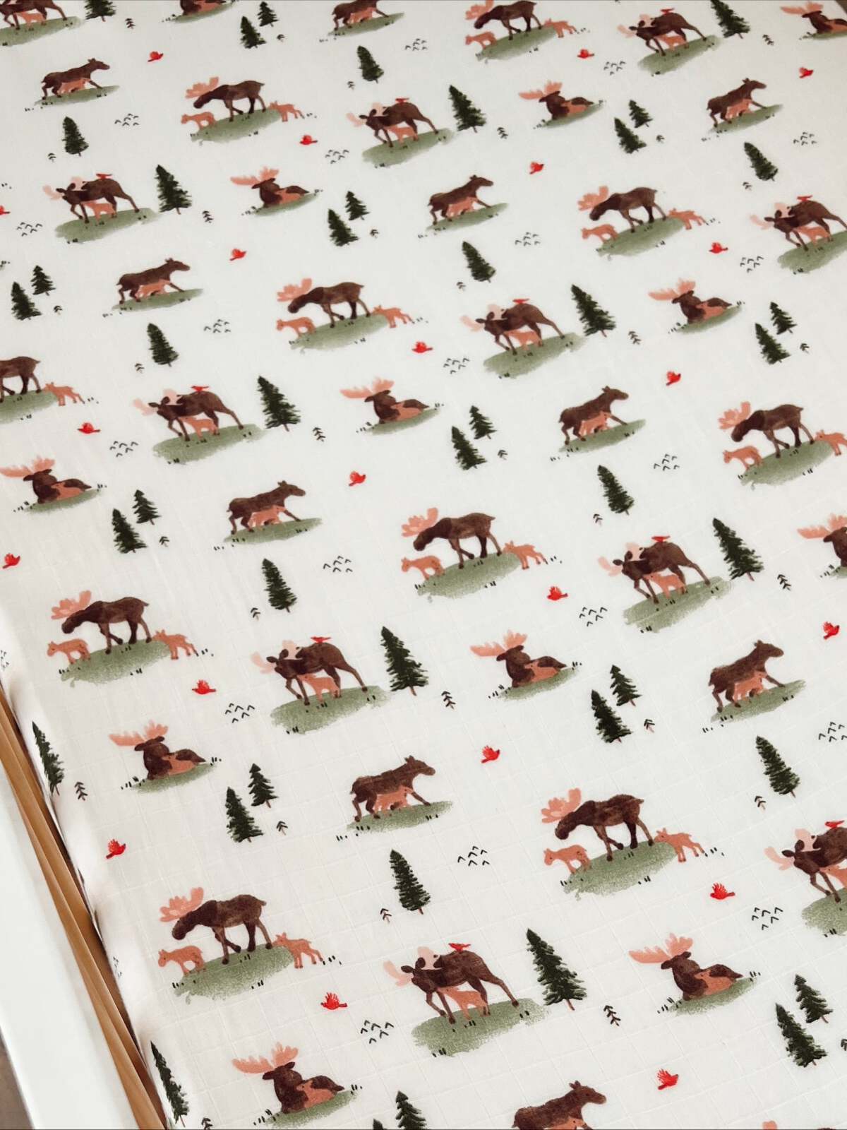 Patterned fabric featuring moose, foxes, trees, and red leaves on a white background.
