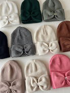 Colorful beanie hats with bows, arranged in a grid on a light background.