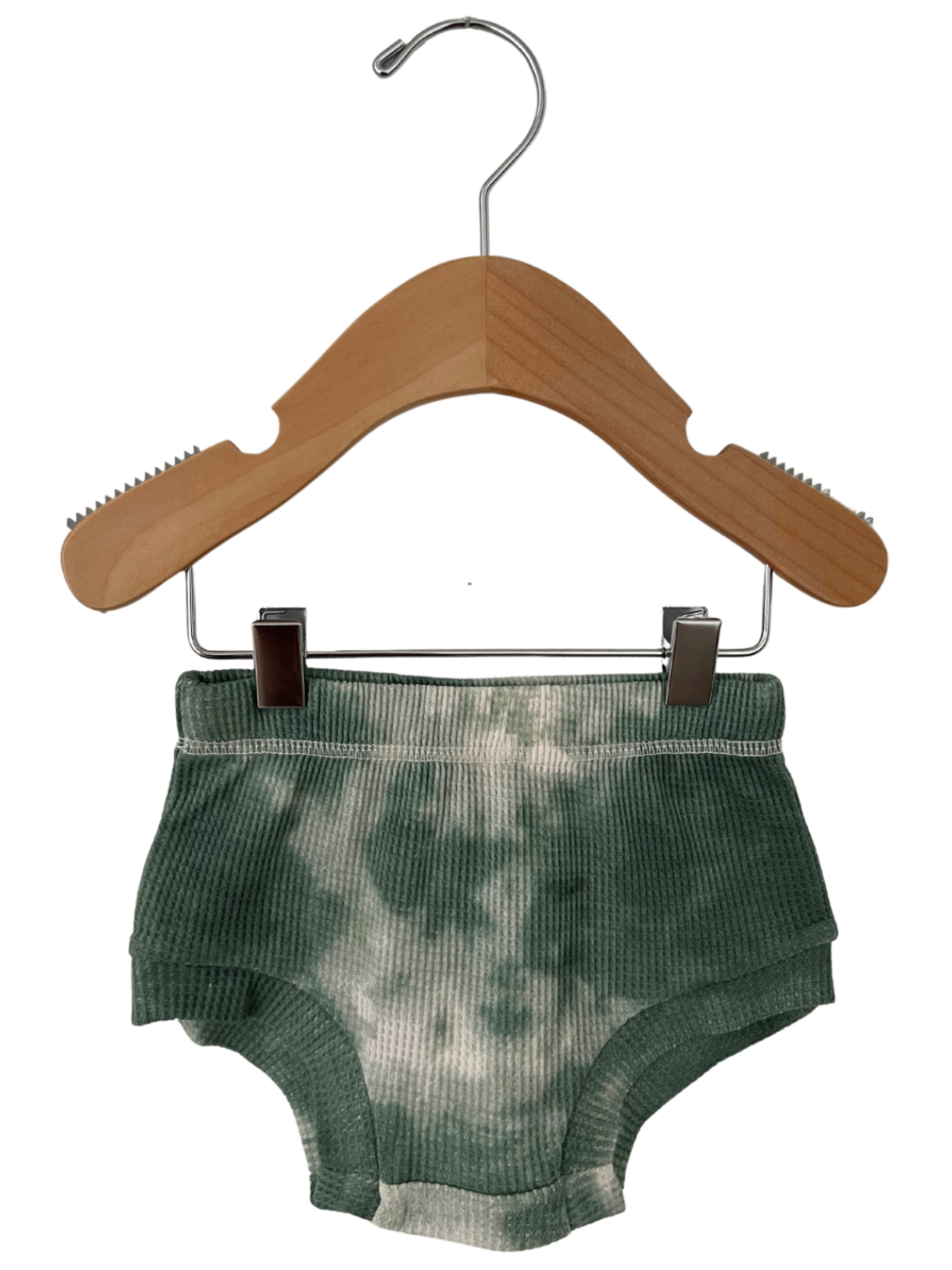 Green tie-dye child shorts hanging on a wooden hanger against a white background.