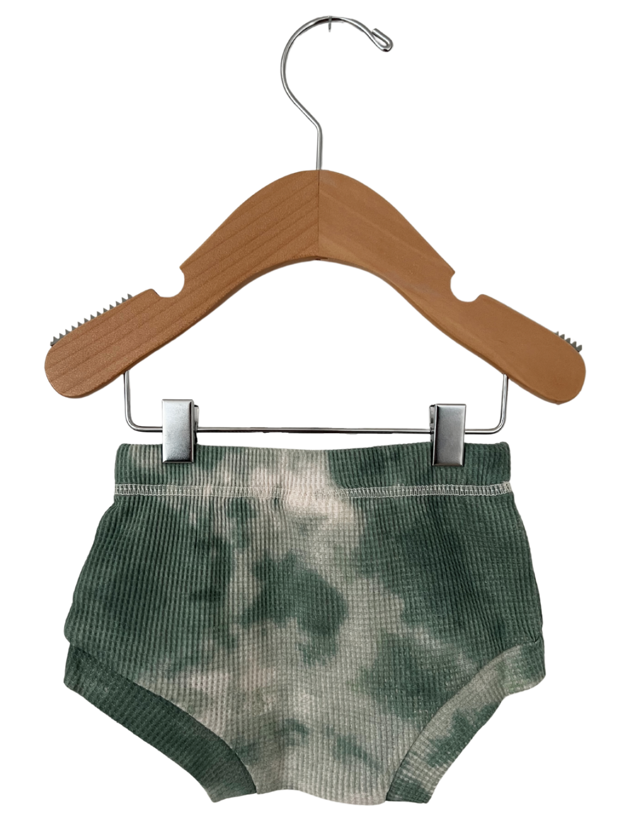 Green tie-dye shorts hanging on a wooden hanger against a white background.