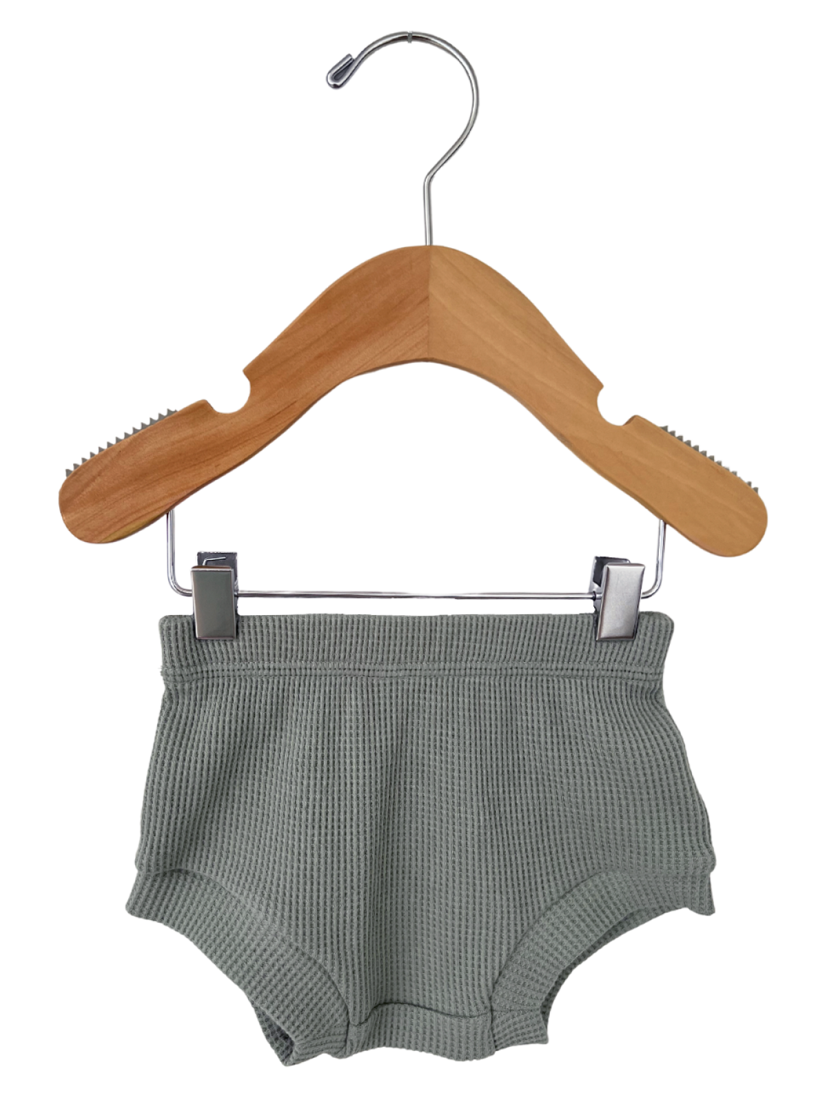 Green waffle-textured toddler shorts hanging on a wooden clothes hanger.