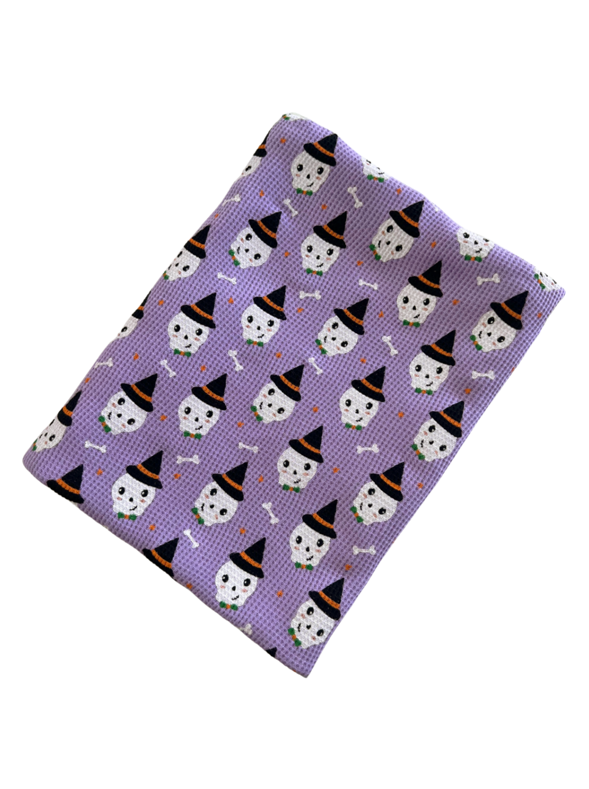 Purple fabric featuring smiling skulls in hats and bones, ideal for festive decorations or crafts.