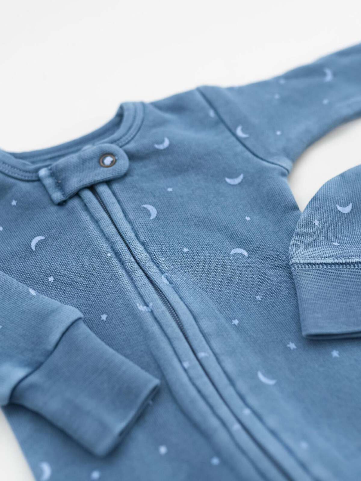Blue baby onesie with moon and star prints, featuring a front snap closure and matching hat.