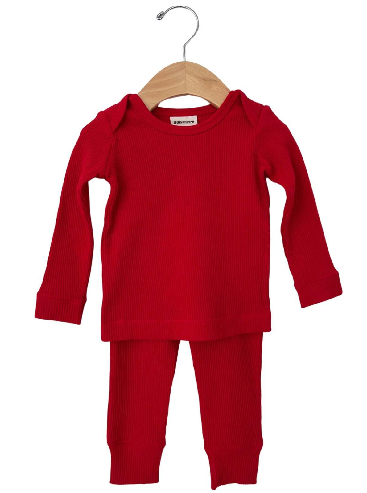 Red ribbed two-piece pajama set hanging on a wooden hanger.