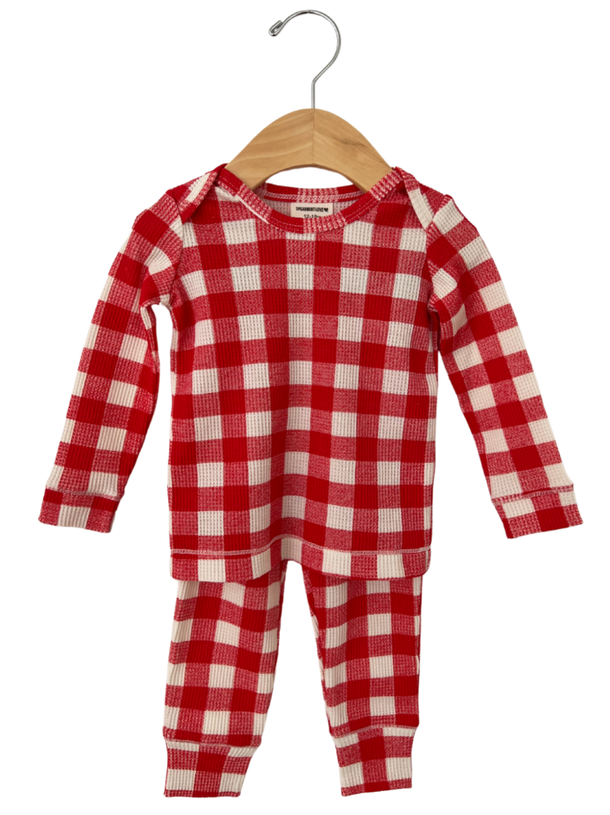 Red and white checkered infant pajamas hanging on a wooden hanger against a white background.