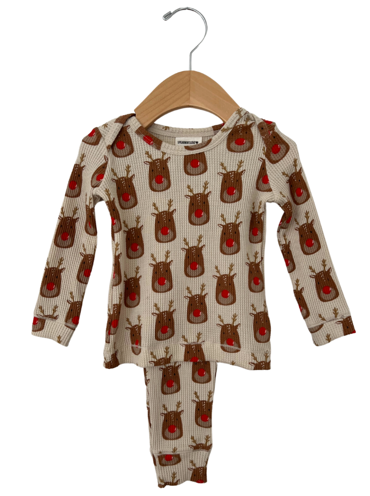 Reindeer-patterned children's pajama set on a wooden hanger, featuring long sleeves and pants.