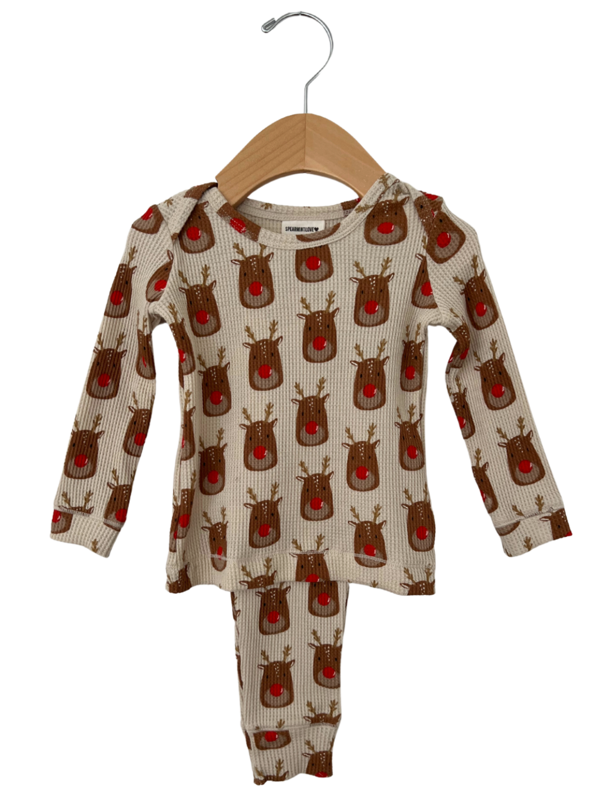 Reindeer-patterned children's pajama set on a wooden hanger, featuring long sleeves and pants.