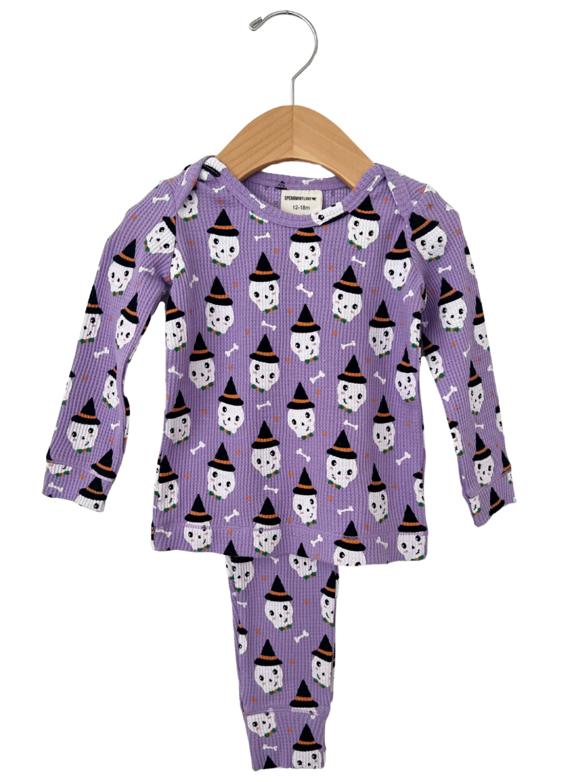Purple pajama set featuring playful ghost and witch hat patterns, hanging on a wooden hanger. For ages 12-18 months.