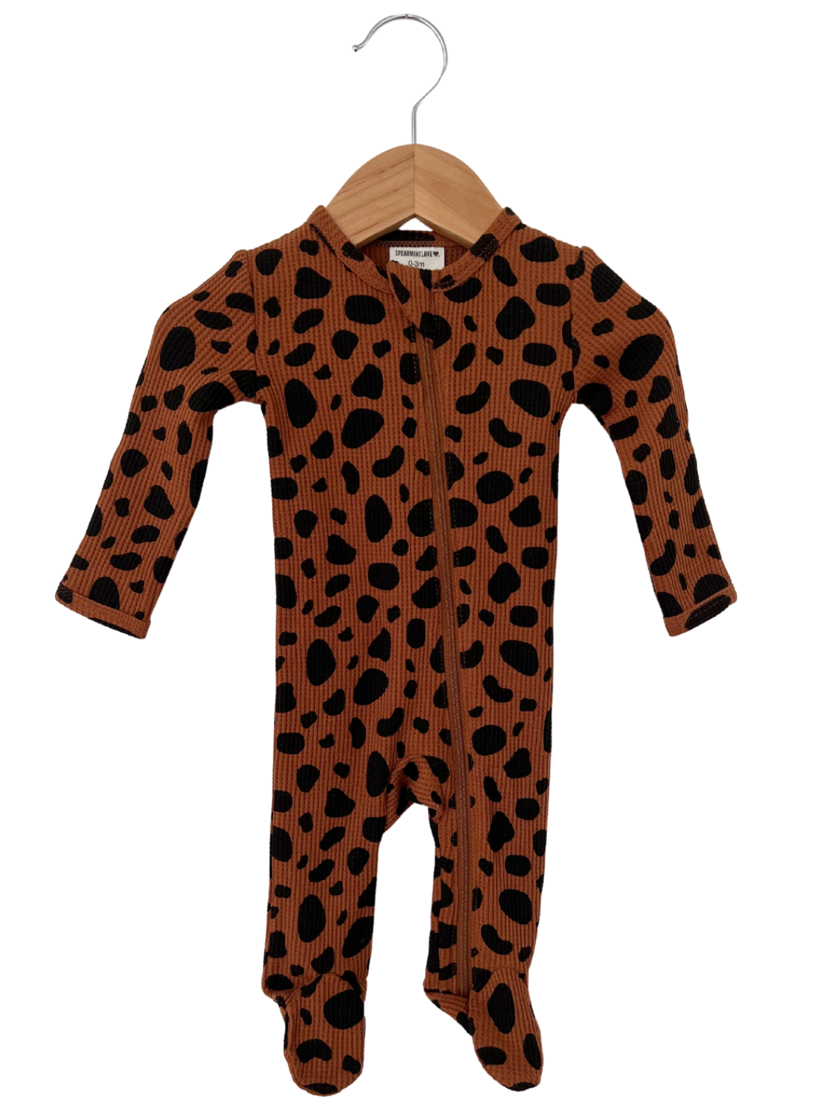 Brown and black polka dot baby onesie on a wooden hanger, featuring a zipper front and footed design.