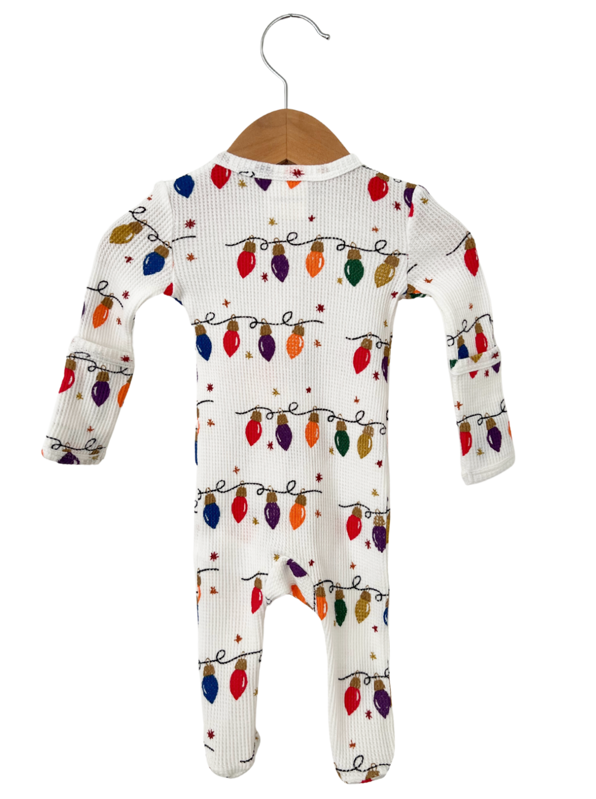 White onesie with colorful Christmas lights and stars pattern, hanging on a wooden hanger.