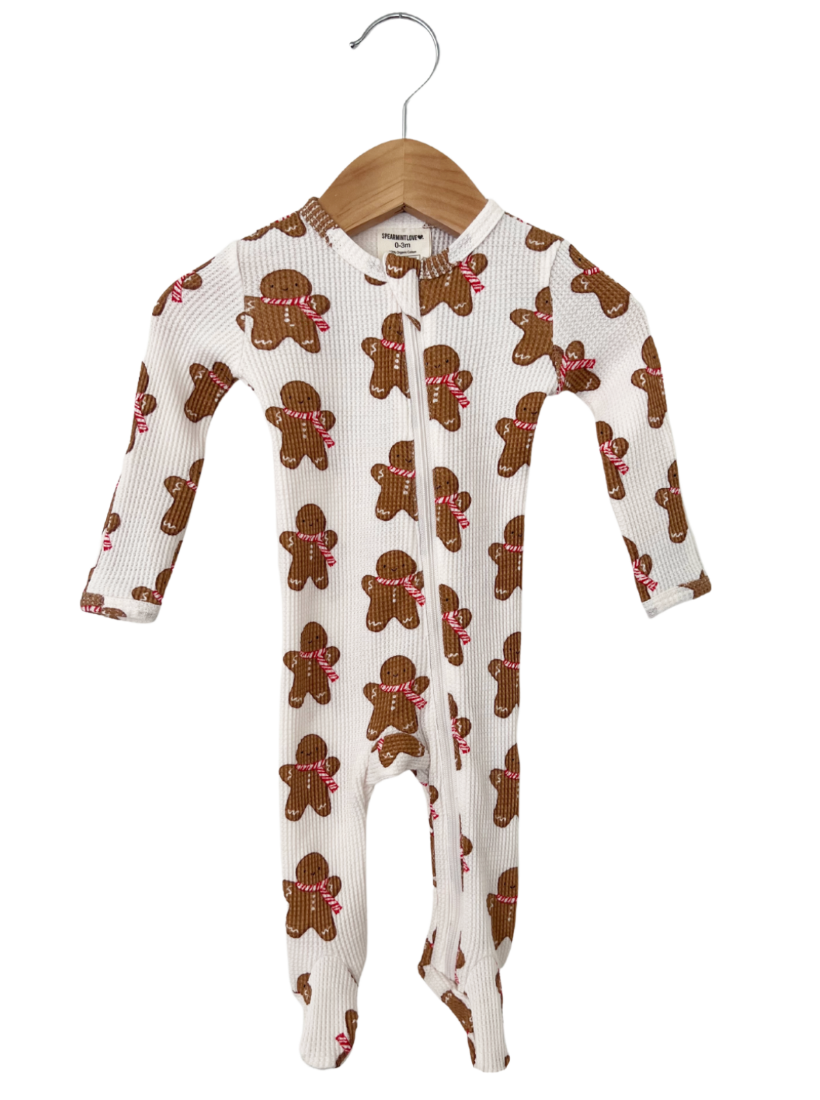 Gingerbread-themed infant onesie hanging on a wooden hanger, featuring a playful design with candy accessories.