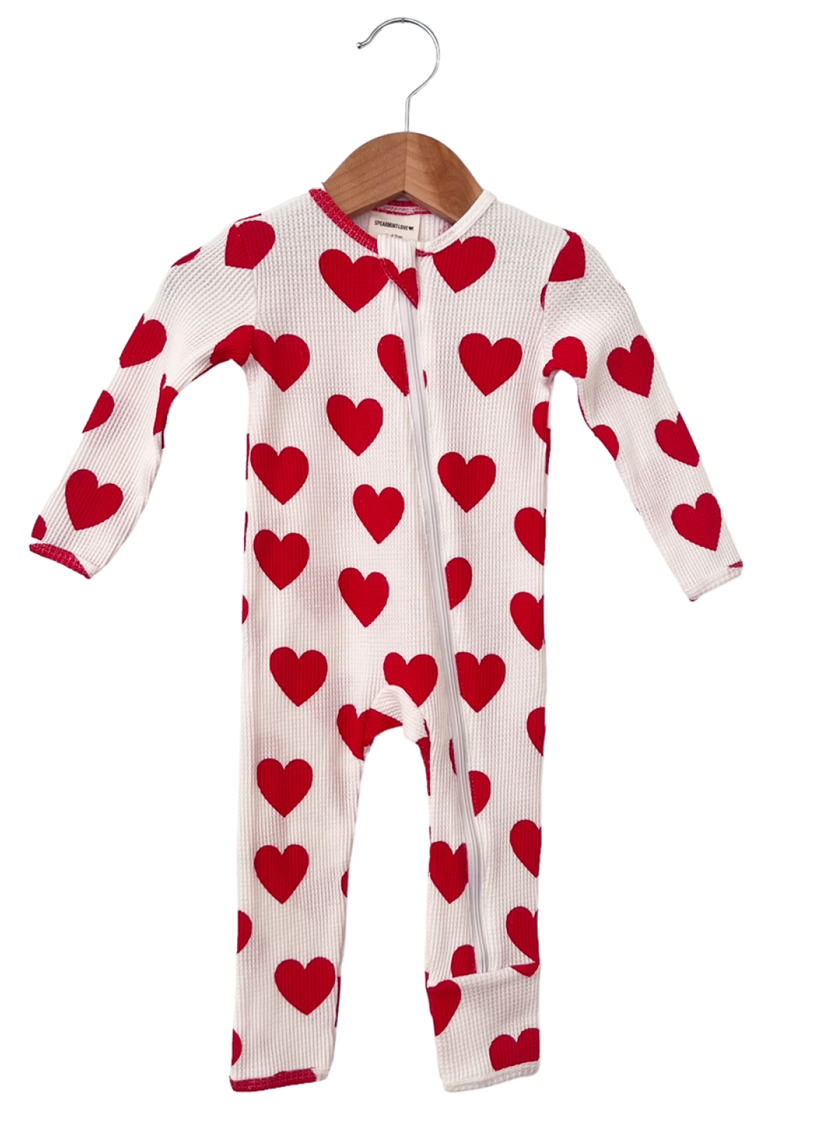 Red heart-patterned baby onesie hanging on a wooden hanger against a white background.