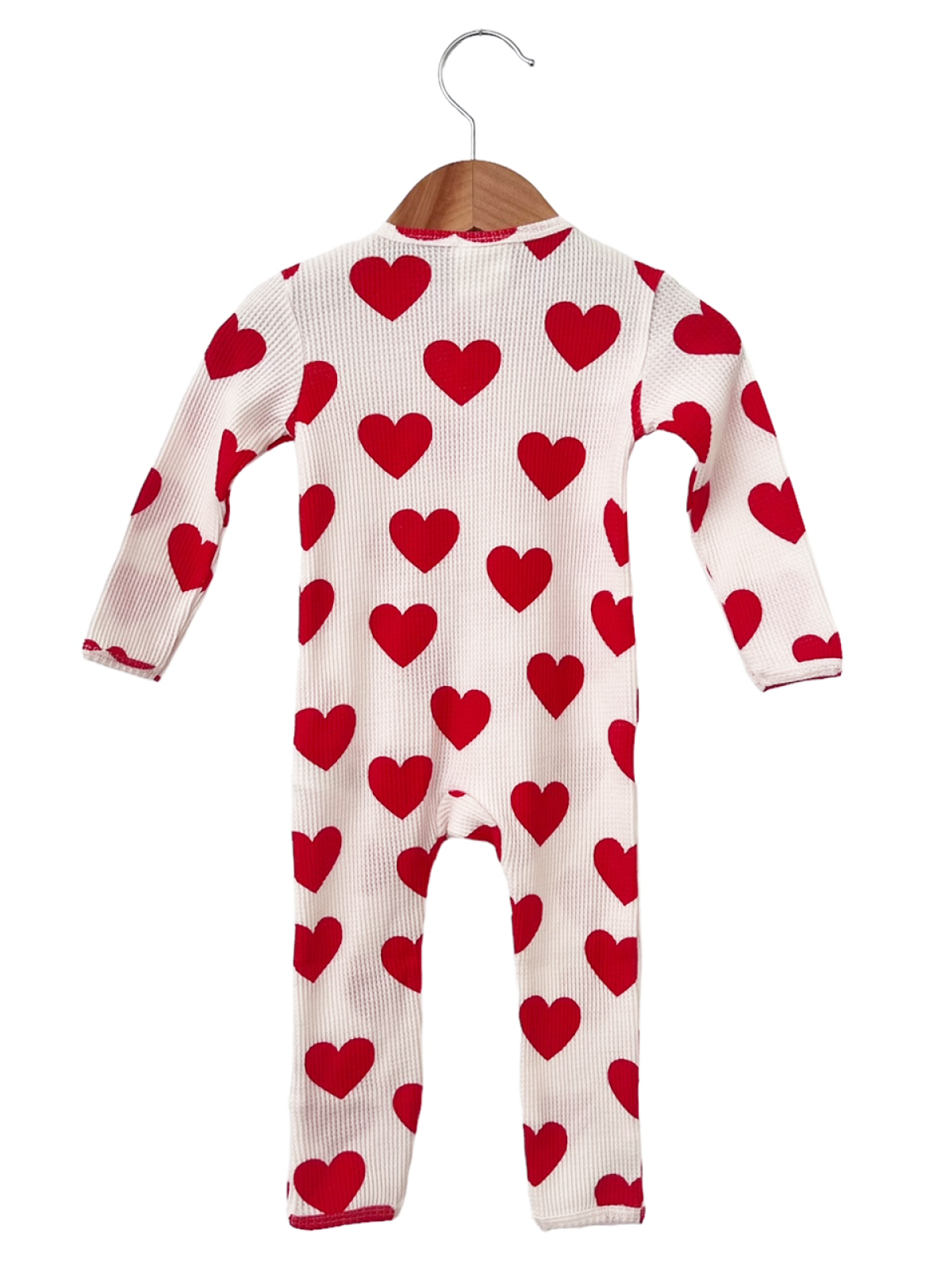 Red heart-patterned infant onesie hanging on a wooden hanger against a white background.