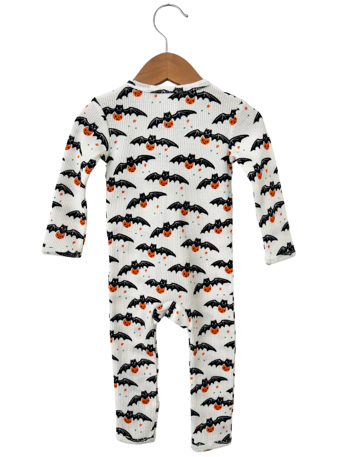 Baby onesie with black bats and orange pumpkins on a white background, hanging on a wooden hanger.