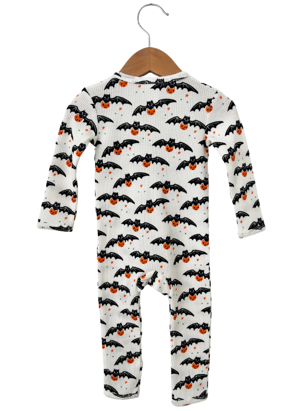 Baby onesie with black bats and orange pumpkins on a white background, hanging on a wooden hanger.