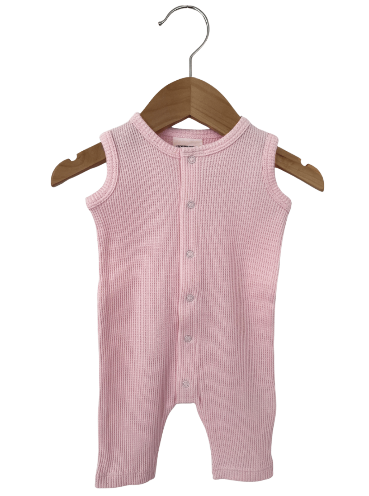 Light pink ribbed baby onesie hanging on a wooden hanger.