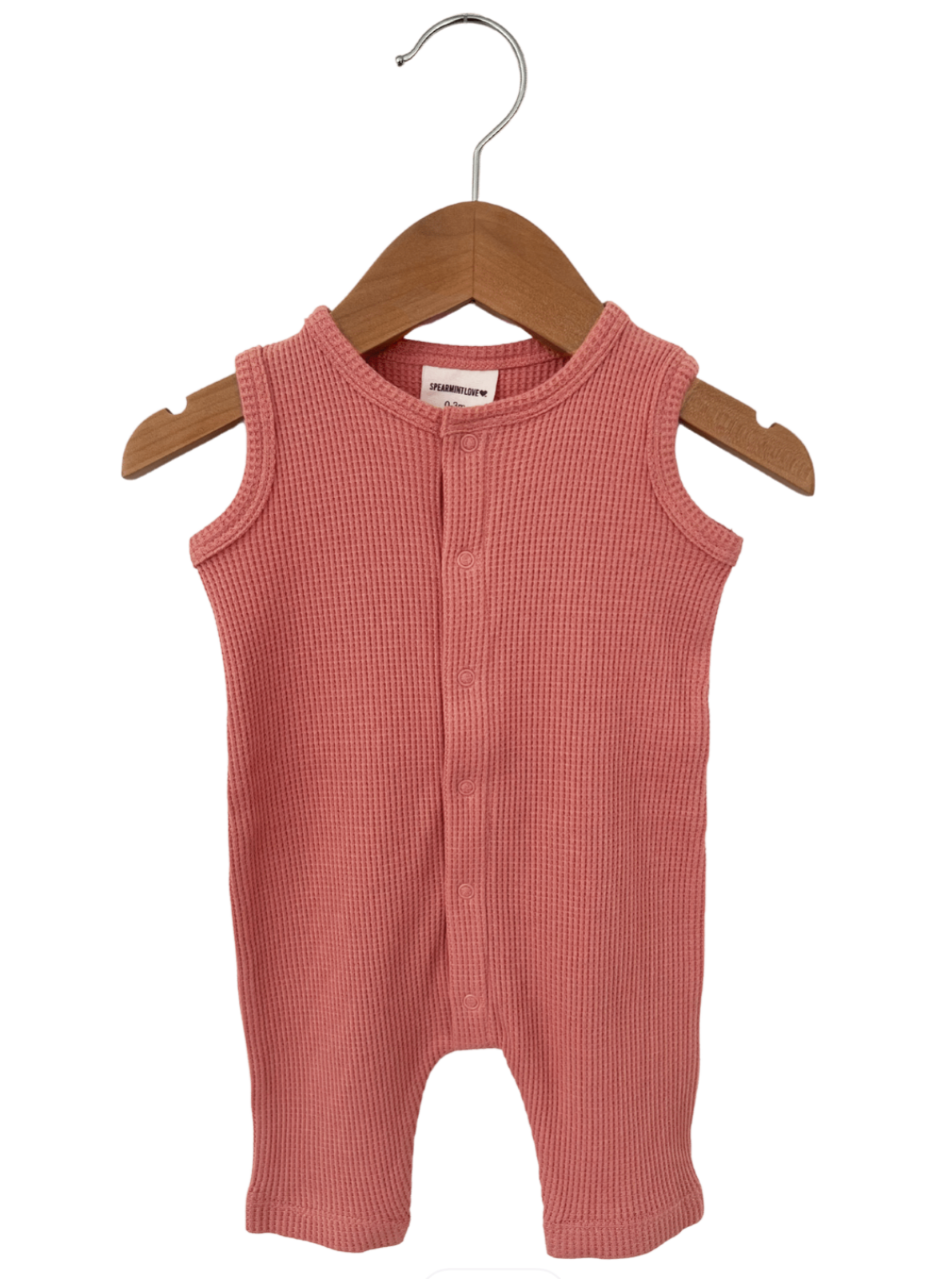Pink ribbed baby romper hanging on a wooden hanger.