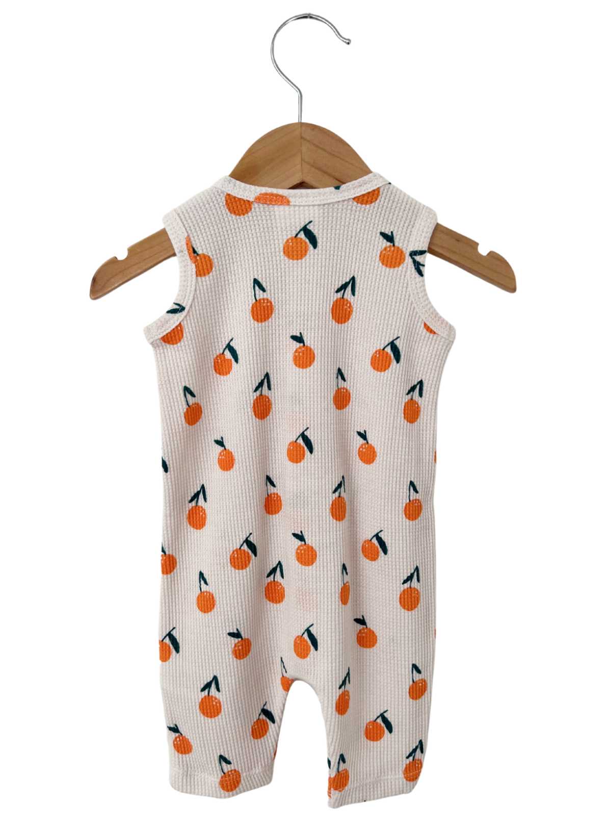 Back view of a baby romper with orange fruit print, hanging on a wooden hanger against a white background.
