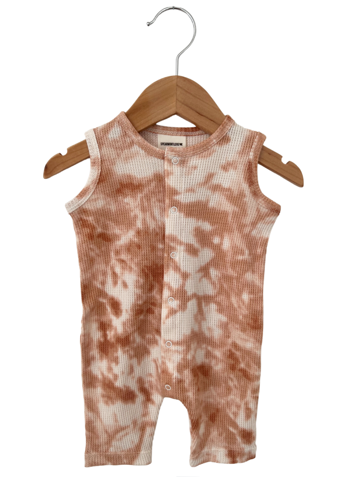 Tan and white tie-dye infant romper hanging on a wooden hanger.