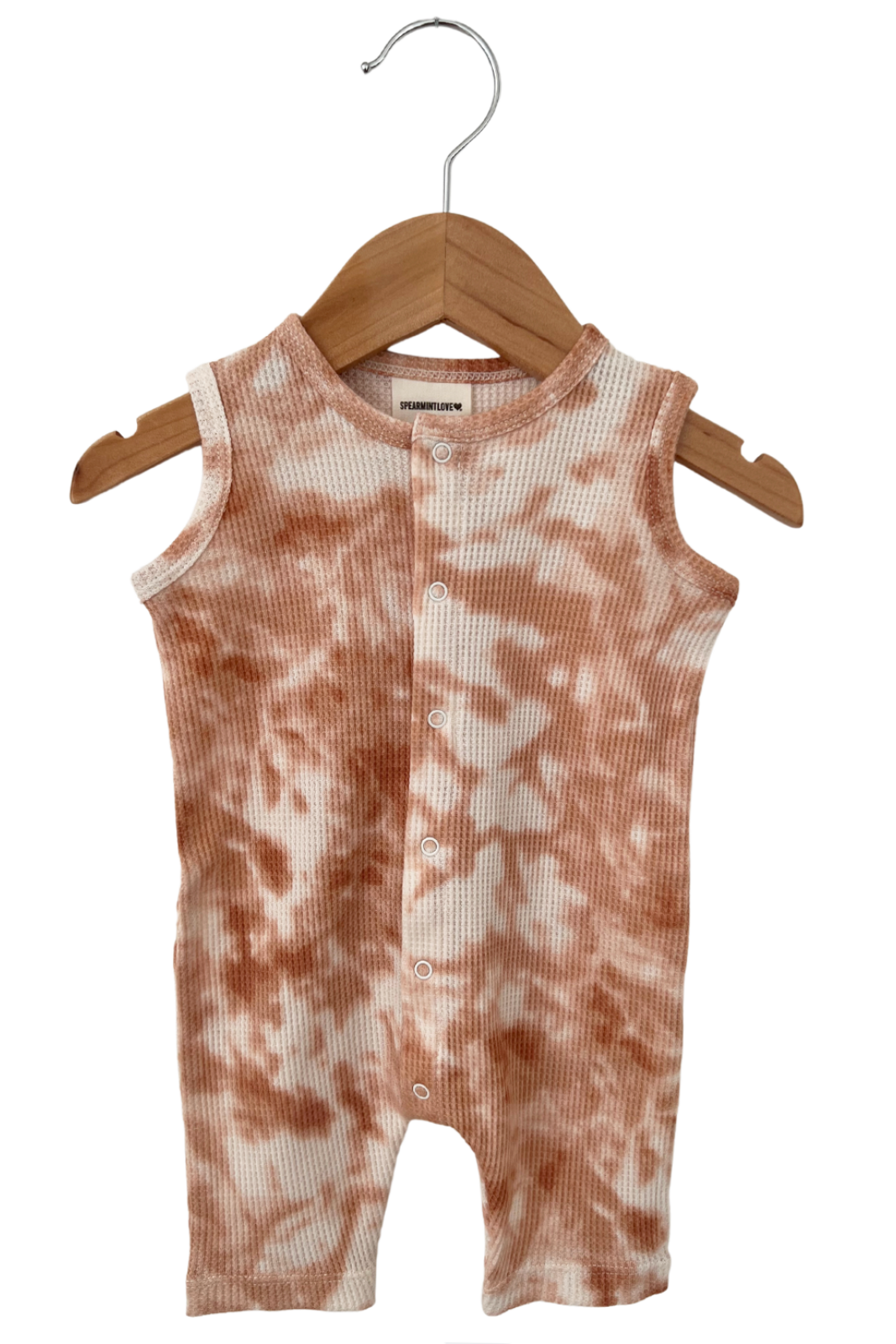 Tan and white tie-dye infant romper hanging on a wooden hanger.
