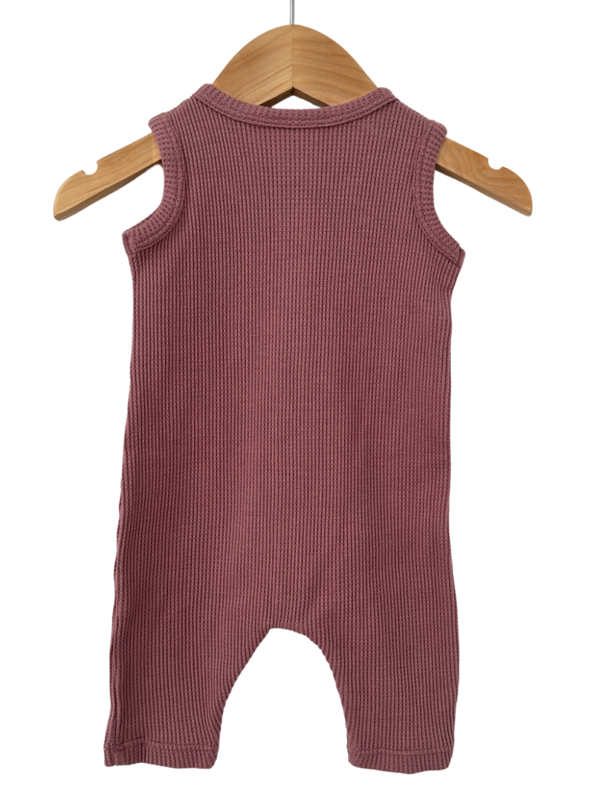 Back view of a ribbed, sleeveless infant romper in soft mauve, hanging on a wooden hanger.