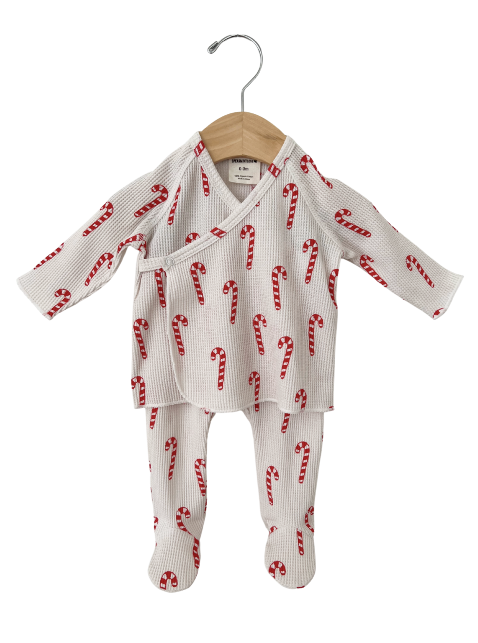 Red and white candy cane patterned baby outfit hanging on a wooden hanger.
