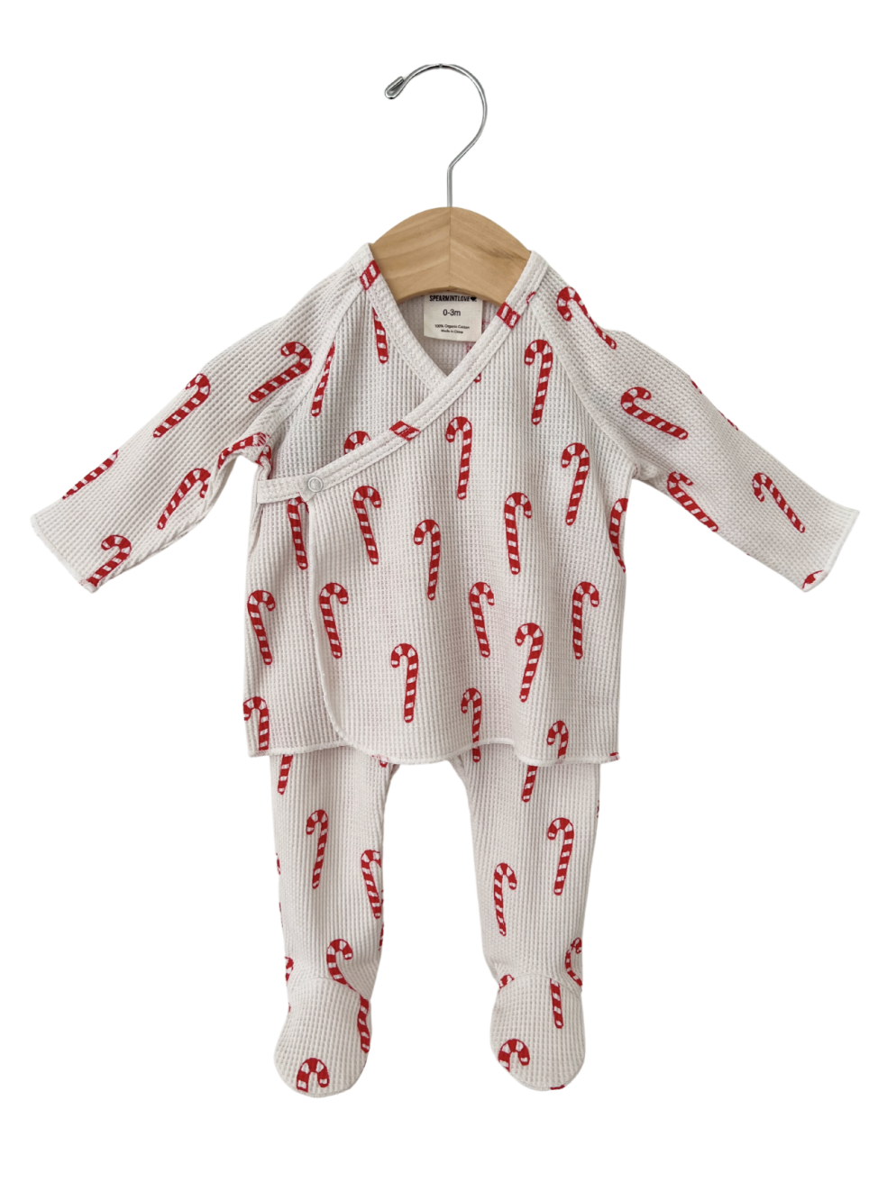 Red and white candy cane patterned baby outfit hanging on a wooden hanger.