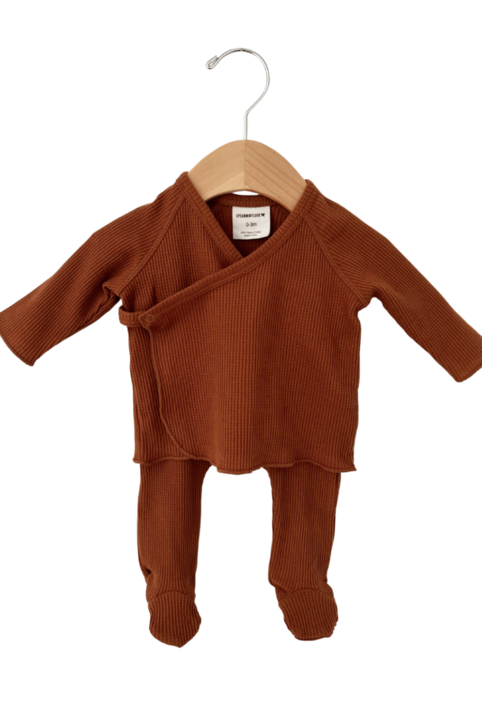 Rust-colored baby outfit hanging on a wooden hanger, featuring long sleeves and matching pants.