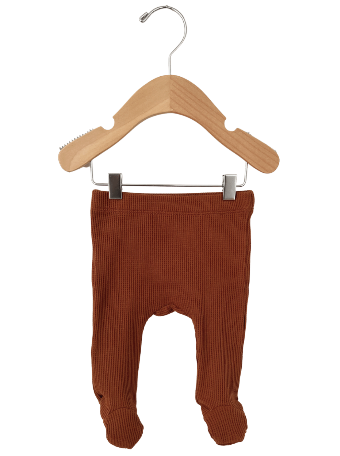 Rust-colored baby leggings hanging on a wooden hanger, showcasing ribbed texture and footed design.