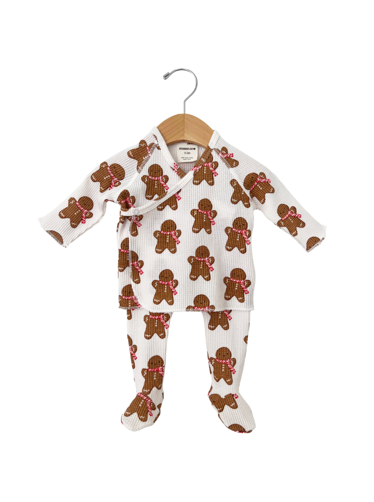 Gingerbread-patterned baby outfit on hanger, featuring long sleeves and matching pants.