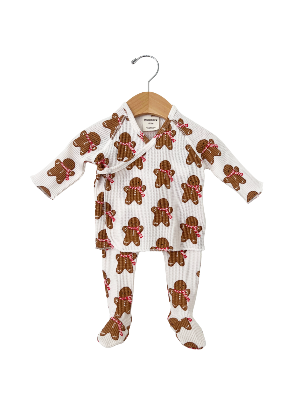 Gingerbread-patterned baby outfit on hanger, featuring long sleeves and matching pants.
