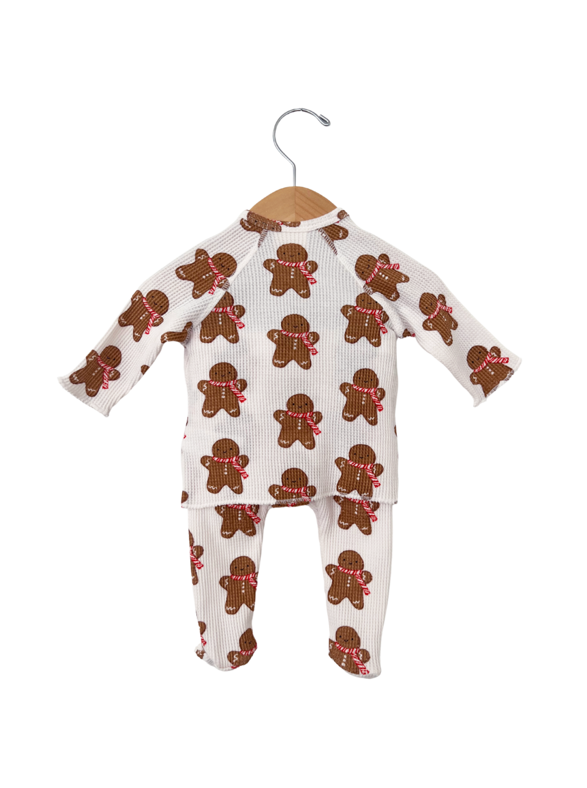 Gingerbread-themed children's pajama set hanging on a wooden hanger.
