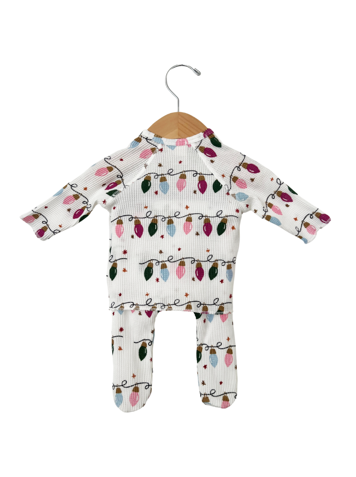 White children's outfit with colorful Christmas lights print, hanging on a wooden hanger.