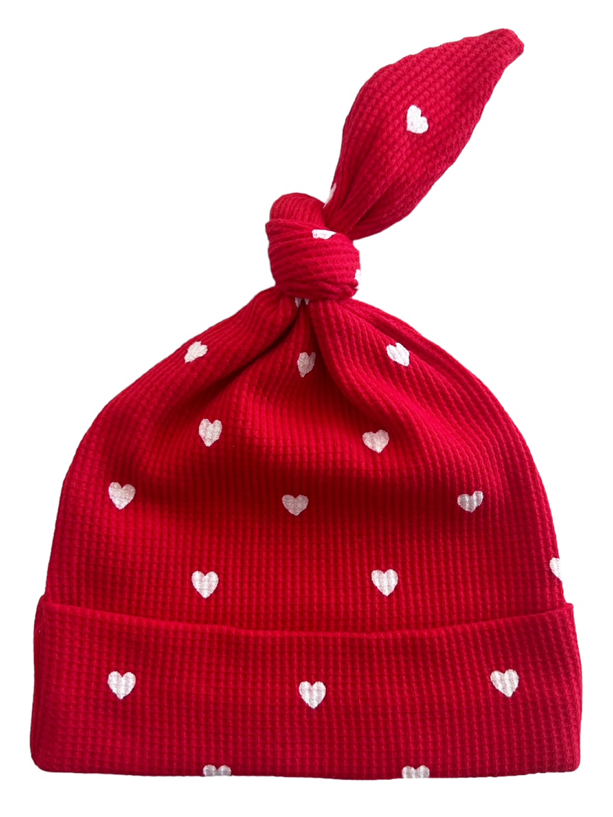 Red knit hat with white heart patterns, featuring a tied top and rolled brim. Perfect for warm, stylish wear.