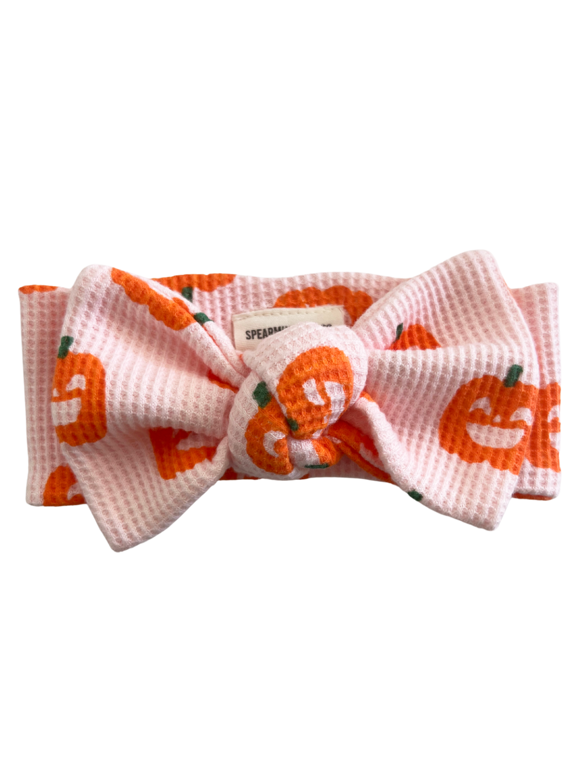Pink headband with orange pumpkin prints and a large bow. Ideal for autumn or festive occasions.