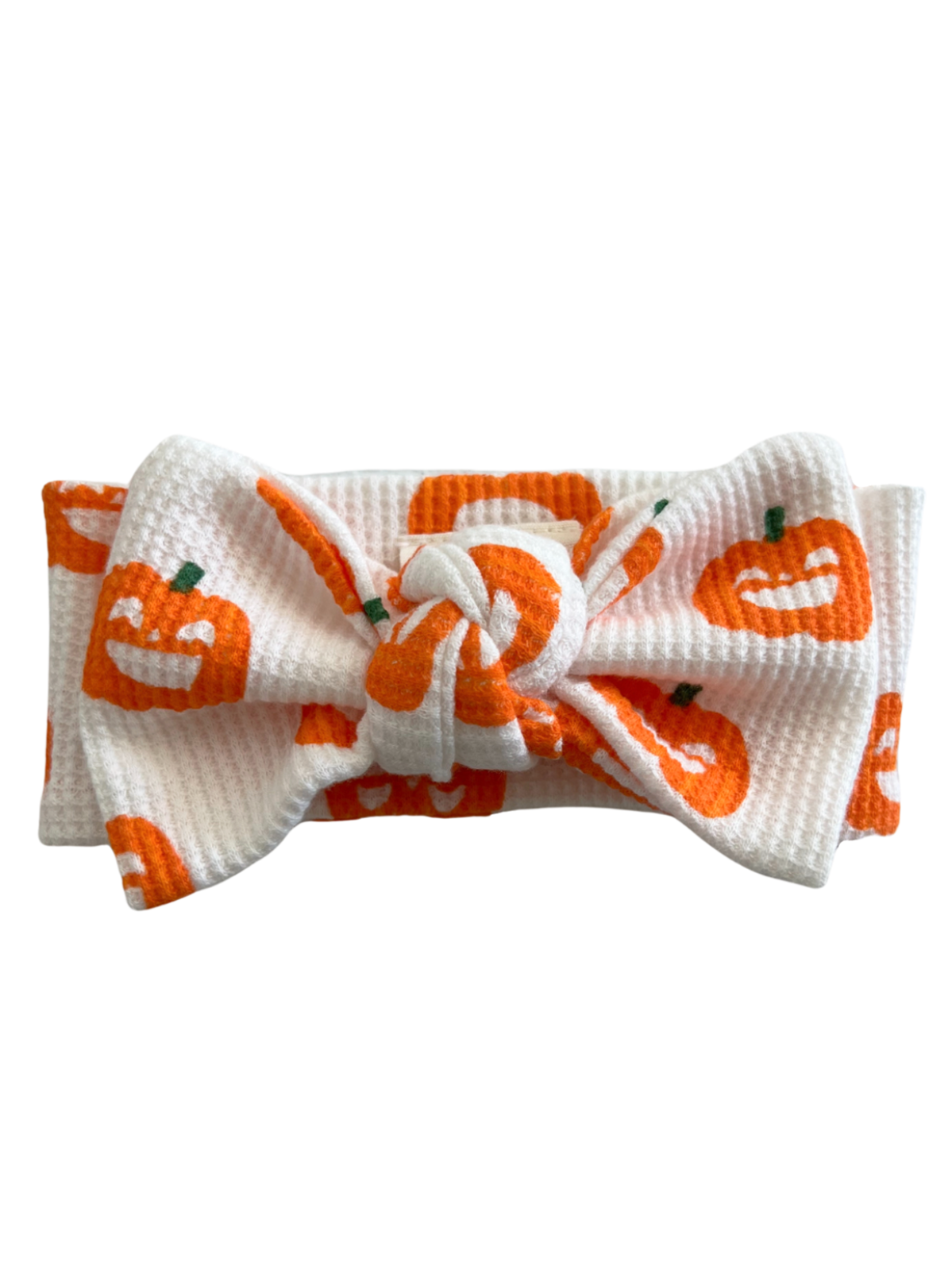 White headband with an orange pumpkin pattern and a knotted bow at the center.