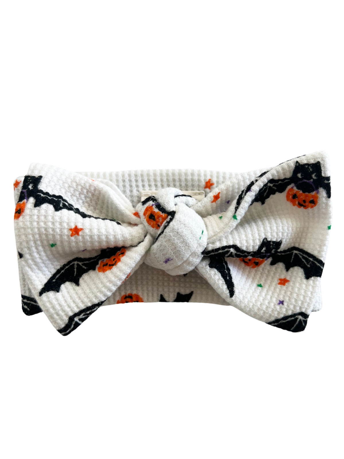 White headband featuring black bats and orange pumpkins on a textured fabric. Perfect for Halloween-themed outfits.