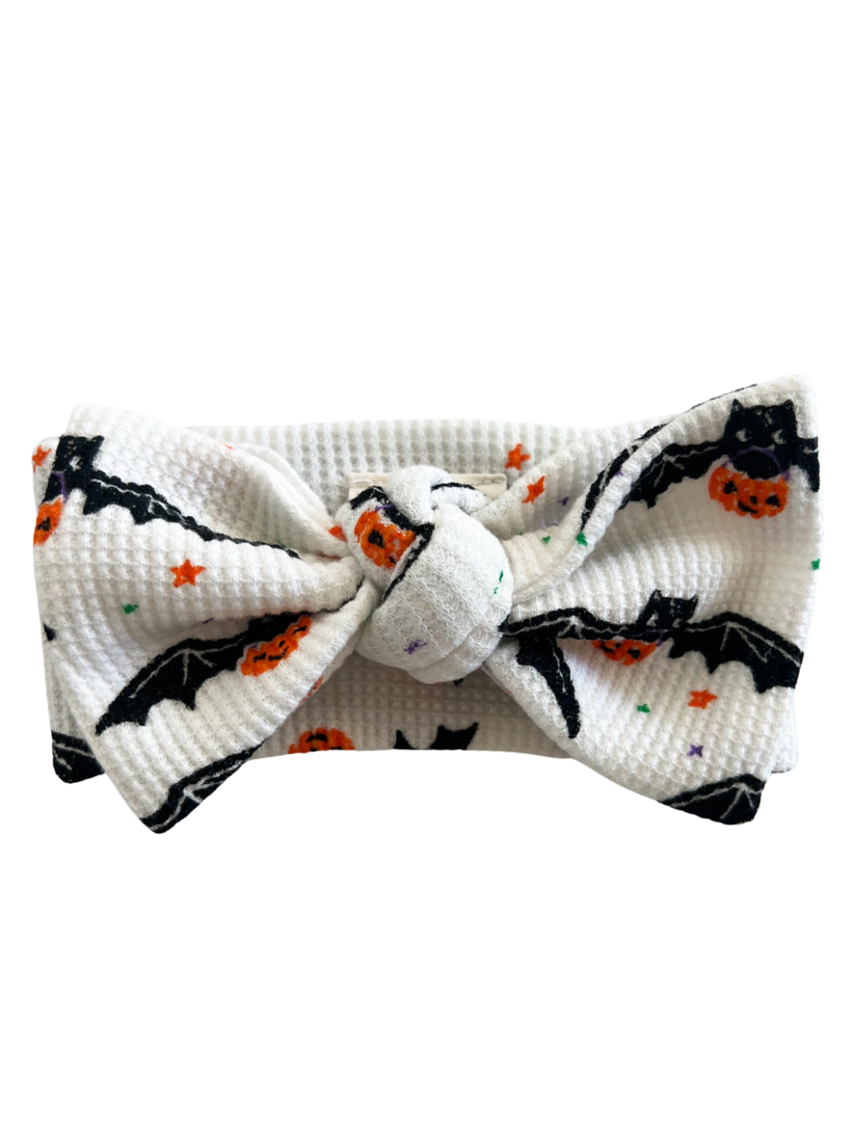 White headband featuring black bats and orange pumpkins on a textured fabric. Perfect for Halloween-themed outfits.