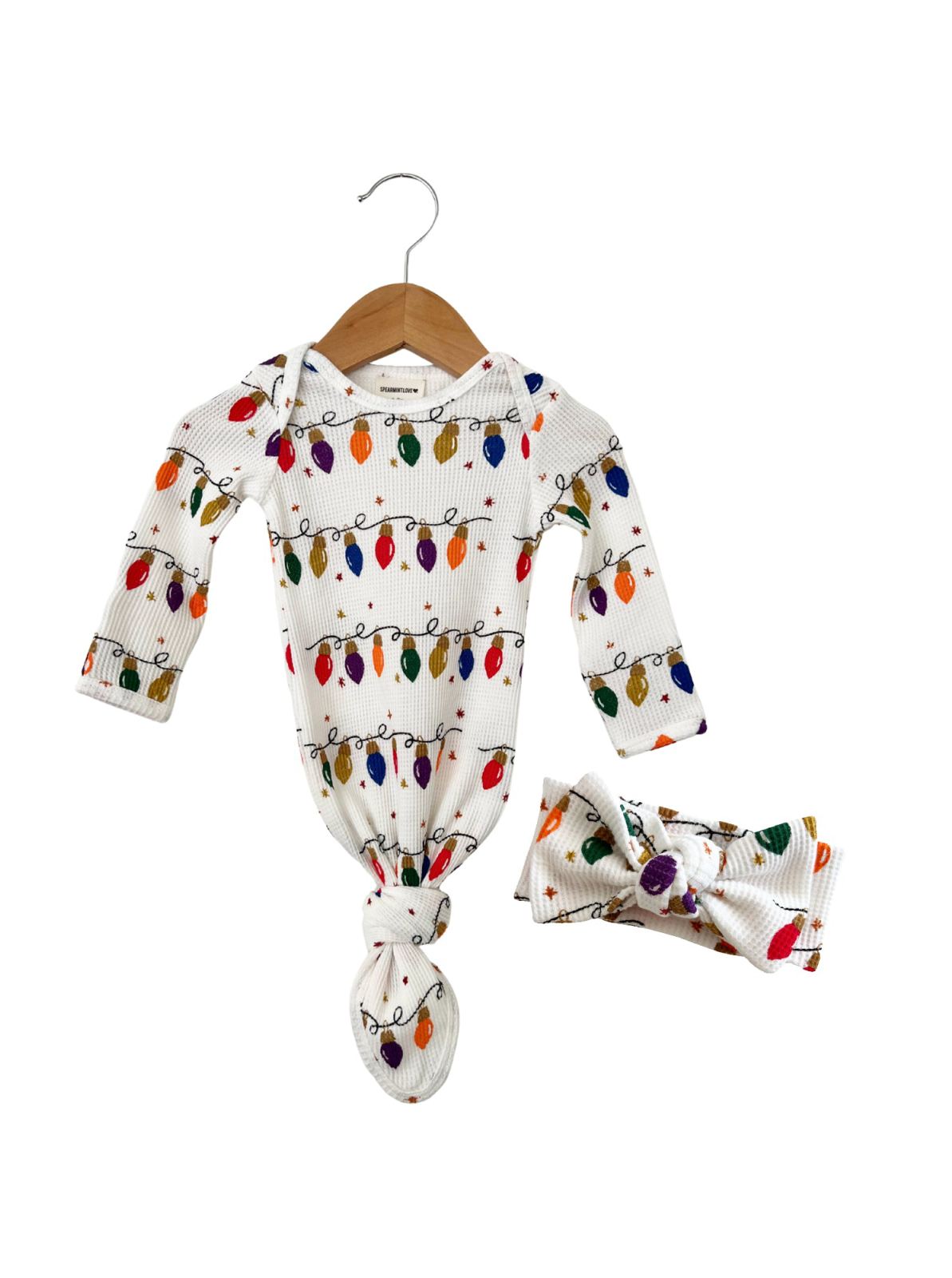 White baby outfit with colorful holiday light print, featuring a knotted gown and matching headband.