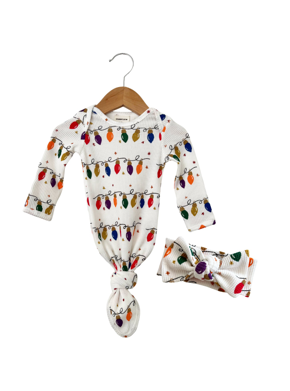 White baby outfit with colorful holiday light print, featuring a knotted gown and matching headband.