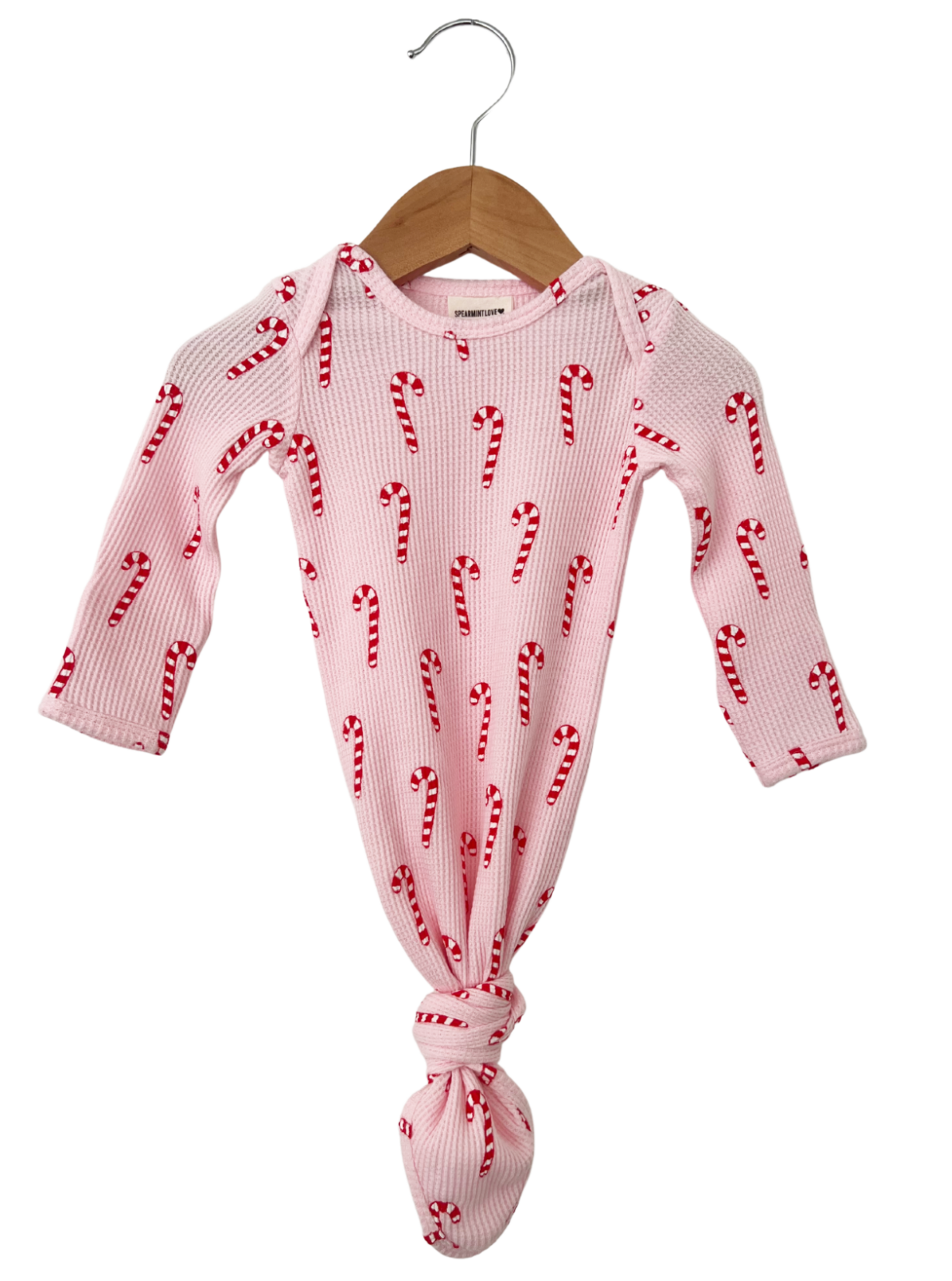 Pink baby onesie with a candy cane pattern, hanging on a wooden hanger. Perfect for festive occasions.