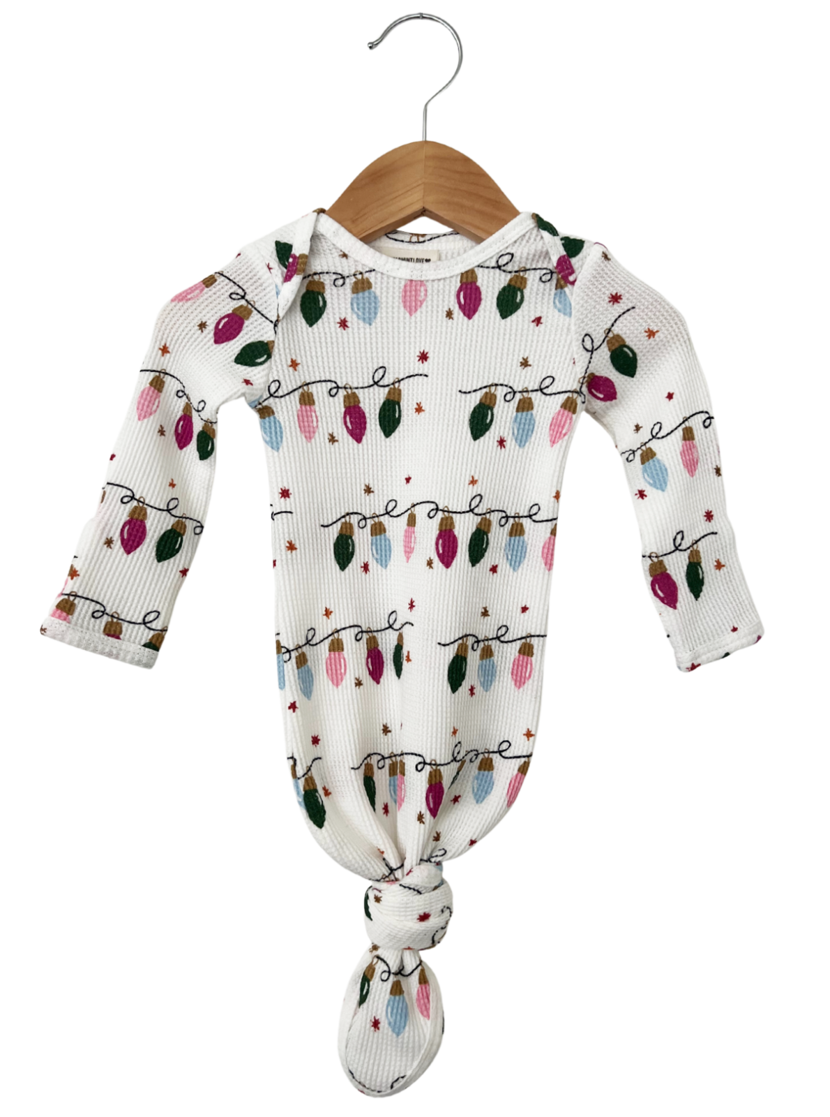White baby onesie with colorful Christmas lights pattern, hanging on a wooden hanger.