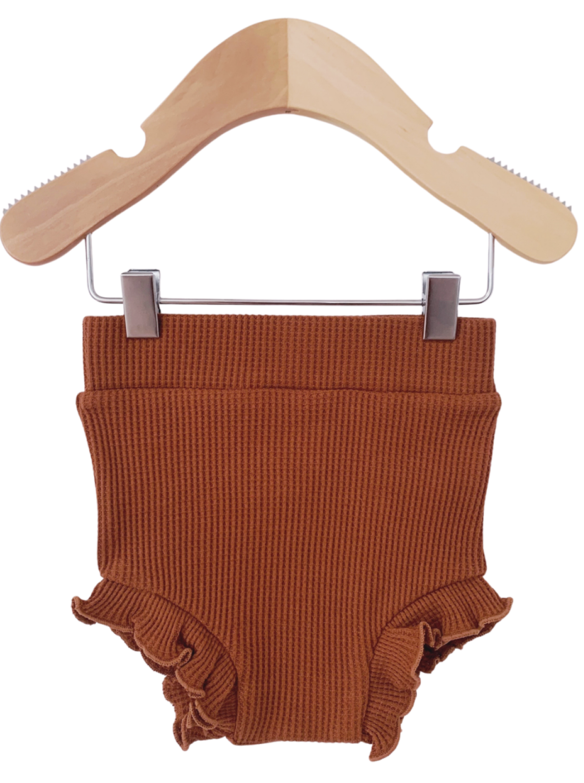 Brown ribbed baby shorts with ruffled edges, hanging on a wooden hanger.