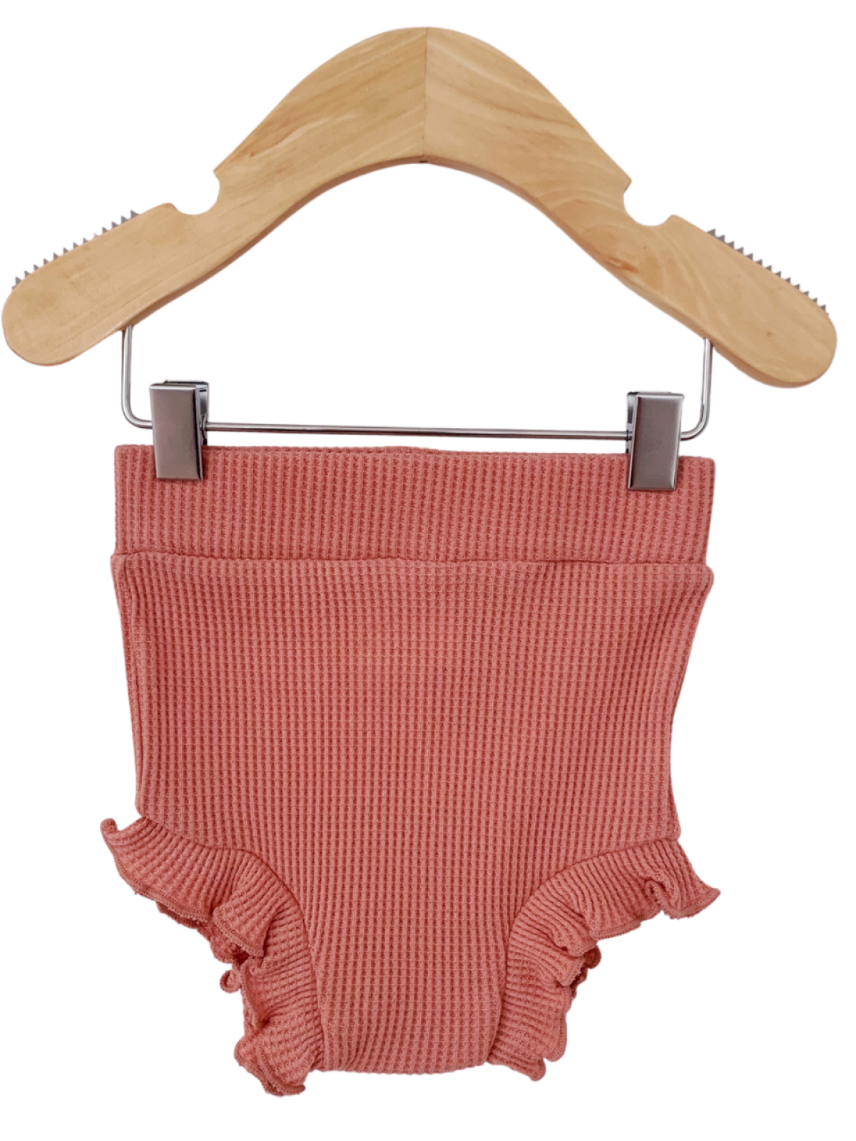 Blush pink toddler swimsuit with ruffled edges, displayed on a wooden hanger.