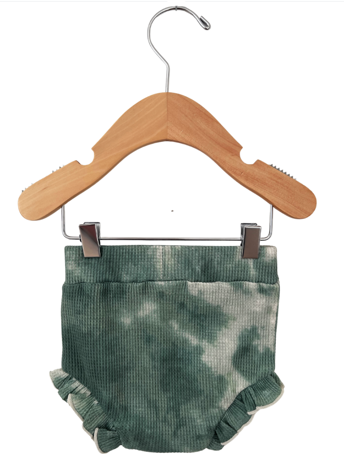 Green tie-dye baby shorts with ruffled edges, hanging on a wooden clothes hanger.