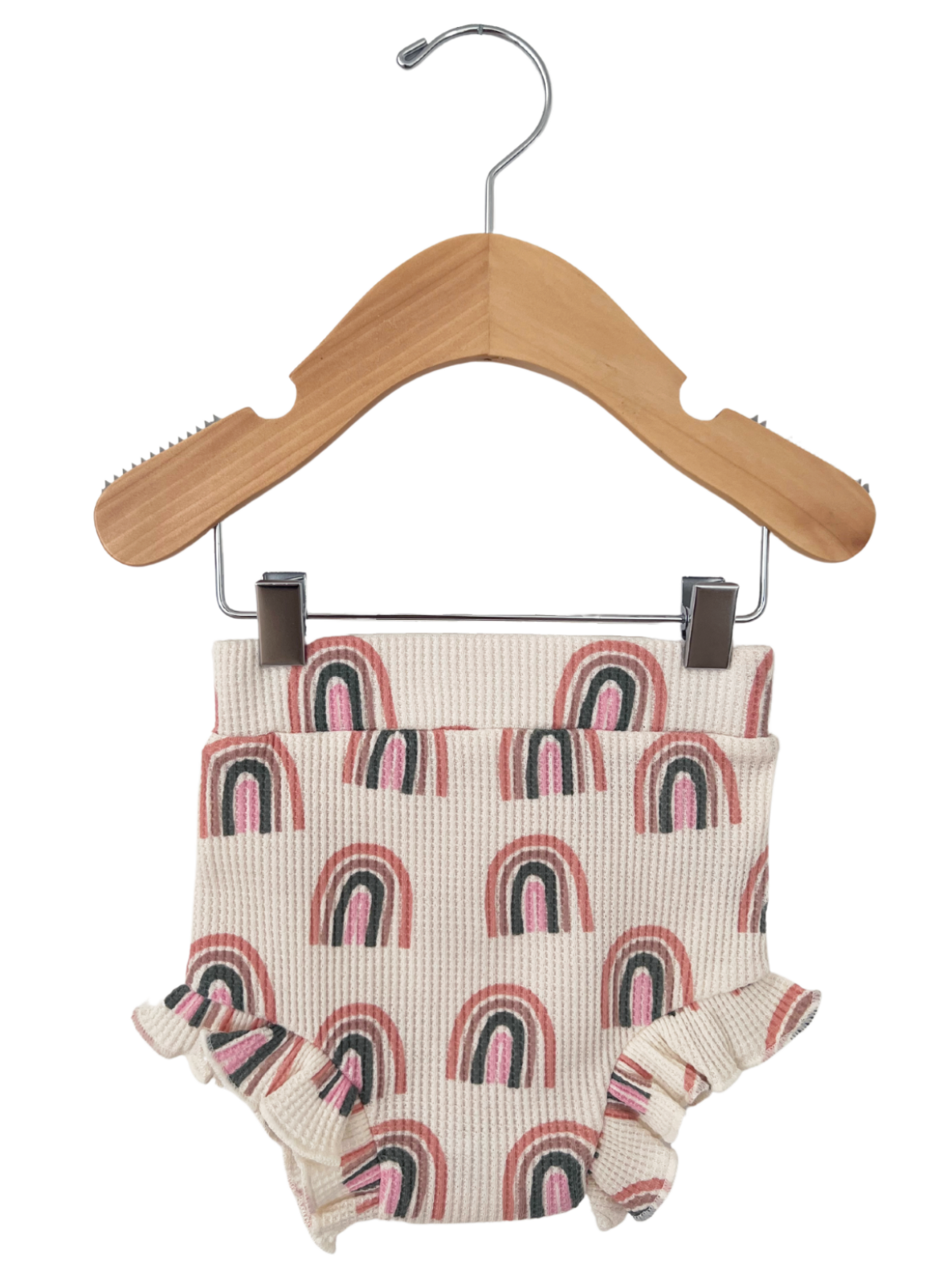 Child's floral rainbow-patterned diaper cover hanging on a wooden hanger. Ruffled edges add a playful touch.