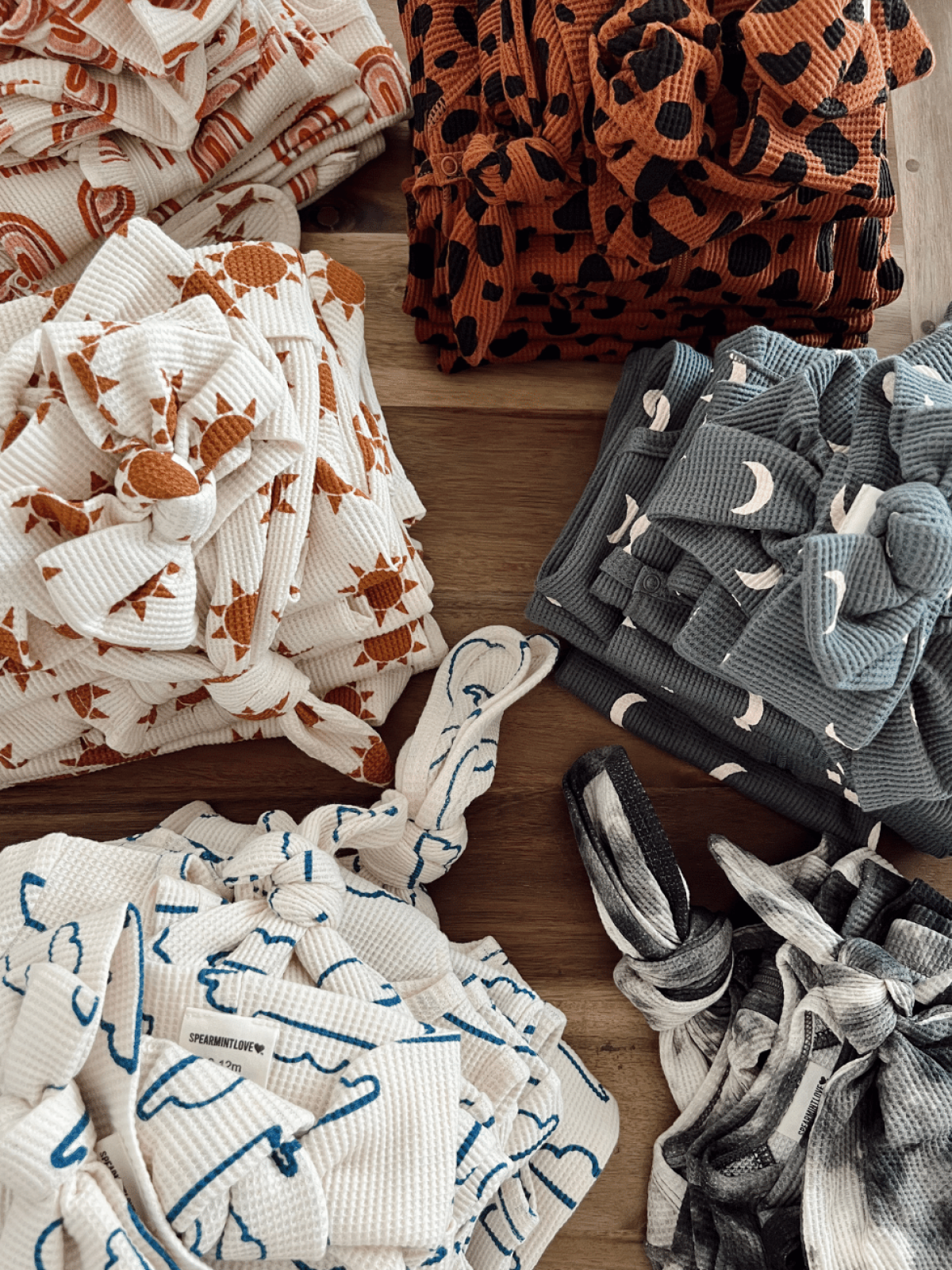 Colorful patterned fabric bundles arranged on a wooden surface, featuring various designs and textures.