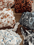 Colorful patterned fabric bundles arranged on a wooden surface, featuring various designs and textures.