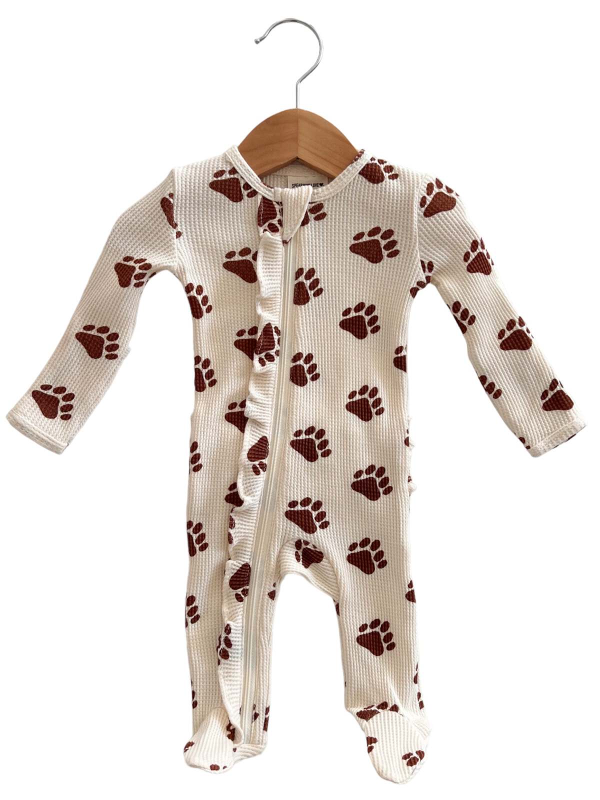 White onesie with brown paw print pattern, hanging on a wooden hanger. Suitable for infants or toddlers.